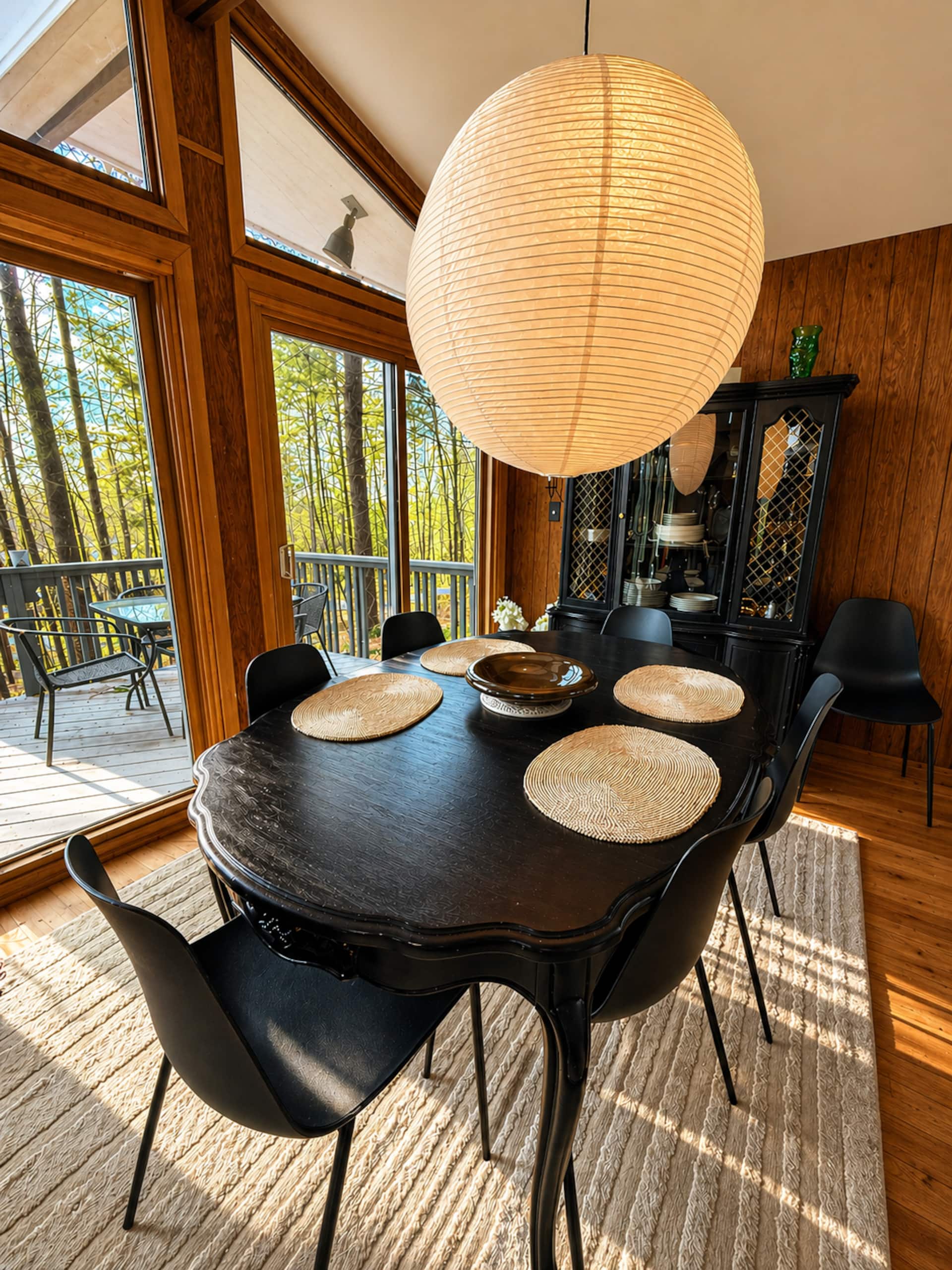 Dining table under a paper lantern beside the deck windows